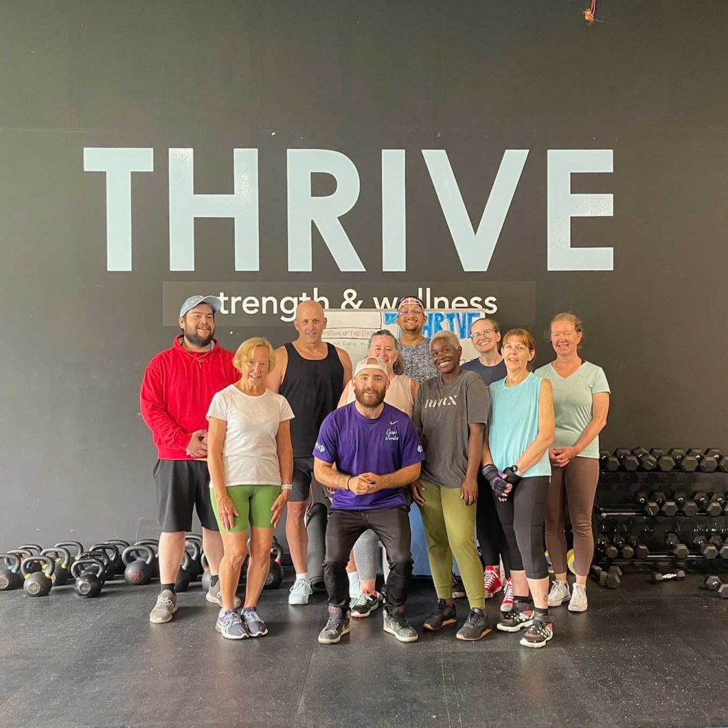 Group fitness class at Thrive Group Strength Training posing with their personal trainer