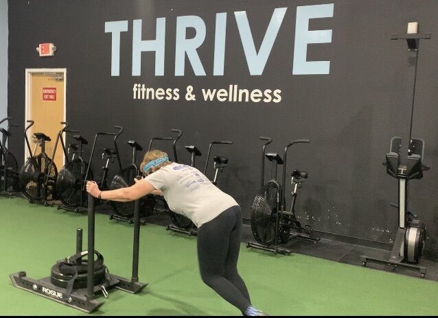 Woman performing a sled push at Thrive Group Strength Training