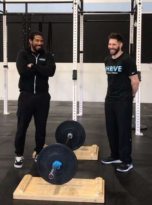 Two personal trainers posting with gym equipment at Thrive Group Strength Training